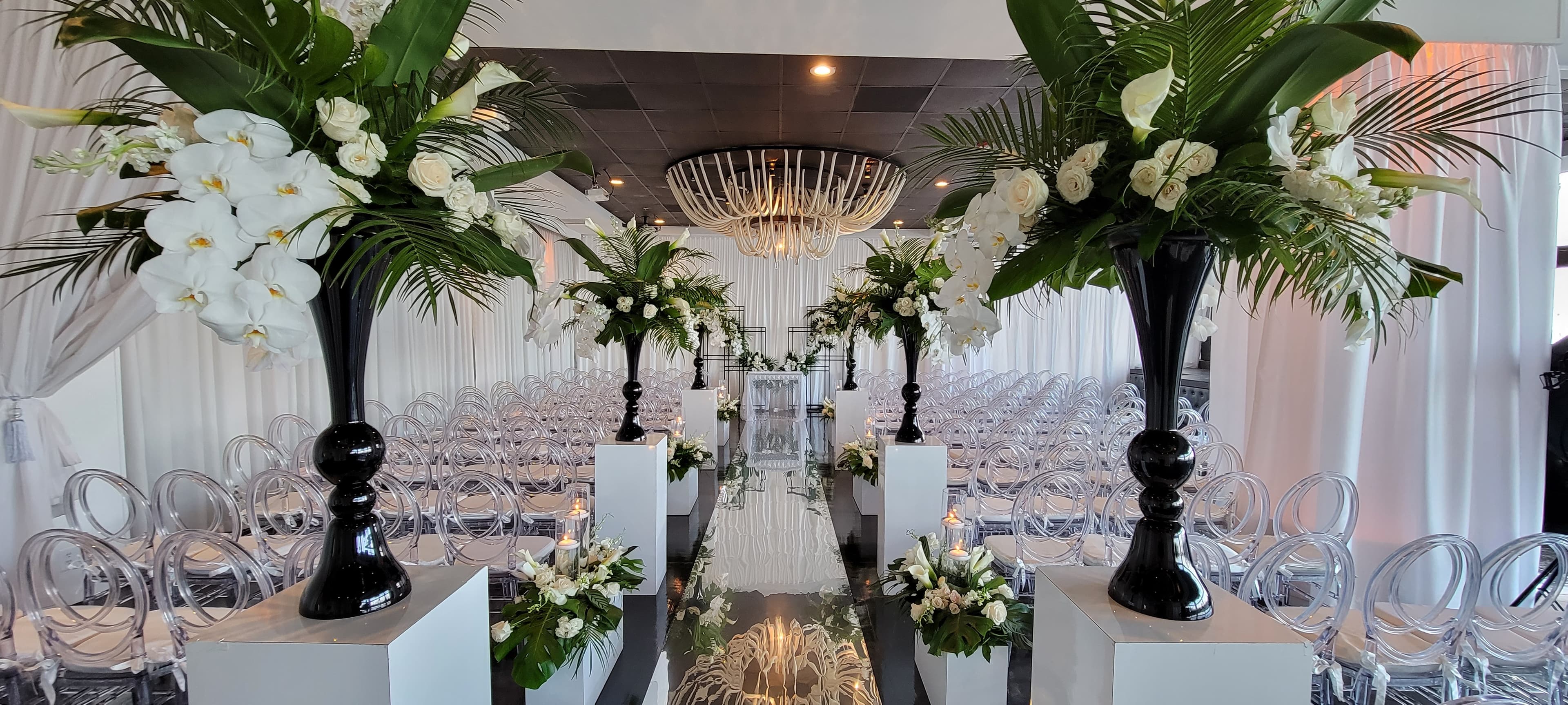 Ceremony aisle lined with towering white orchid arrangements and a mirrored runner