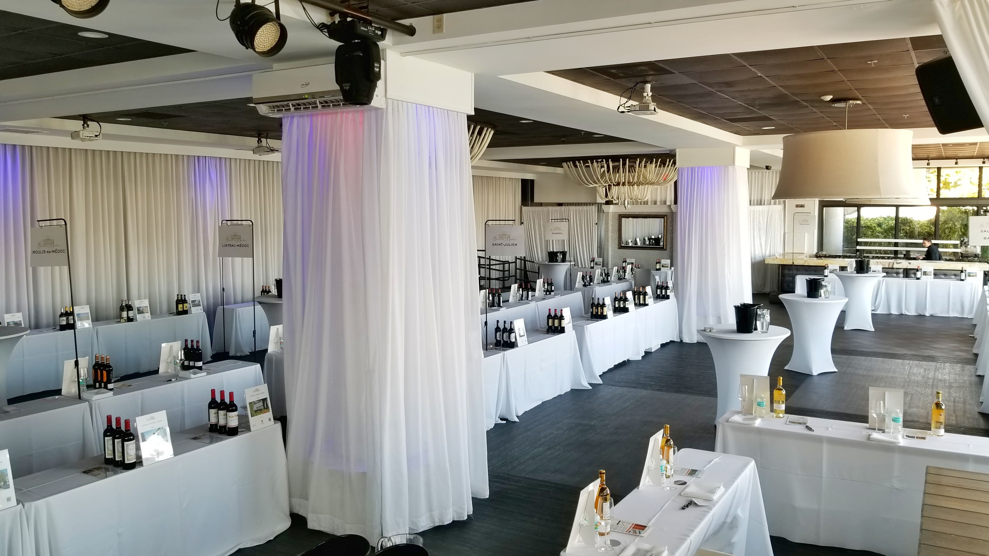 Wine tasting stations arranged across the draped ballroom