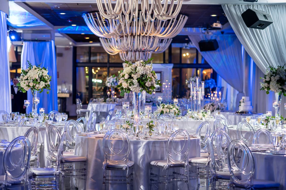 Reception tables and ghost chairs washed in blue uplighting